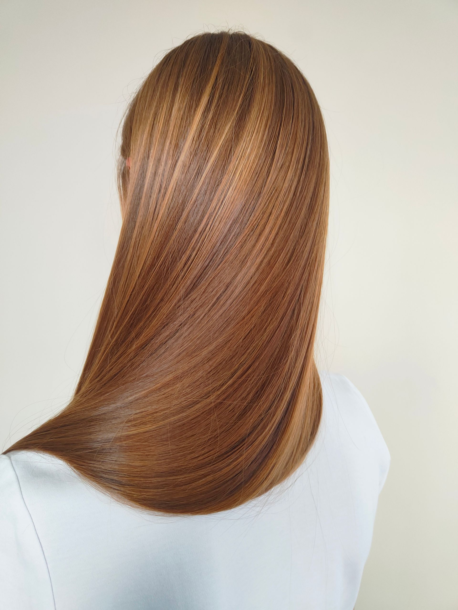 Kobieta z gładkimi, prostymi i odżywionymi włosami po zabiegu pielęgnacyjnym w salonie kosmetycznym